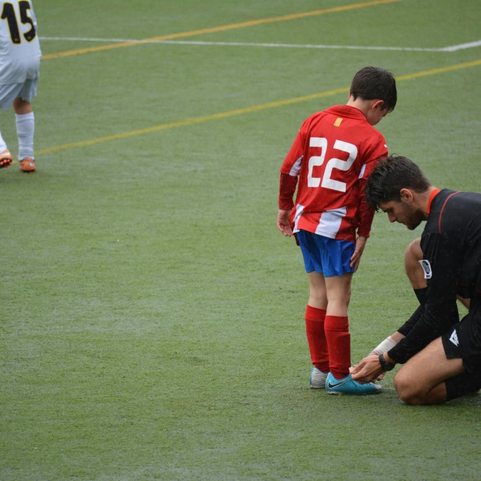 Photo by Adrià Crehuet Cano on Unsplash
A soccer coach tying the shoe of a player on the field