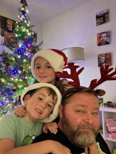 Jeff Davis with his two children, Zoe and Austin. Jeff Davis with his two children: Zoe (9) and Austin (7) wearing red Christmas hats next to a decorated Christmas Tree